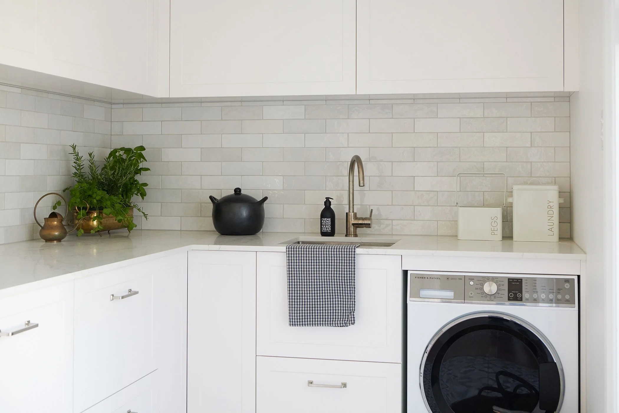Modern residential interior design featuring L-shaped laundry with white shaker cabinets and subway tiles