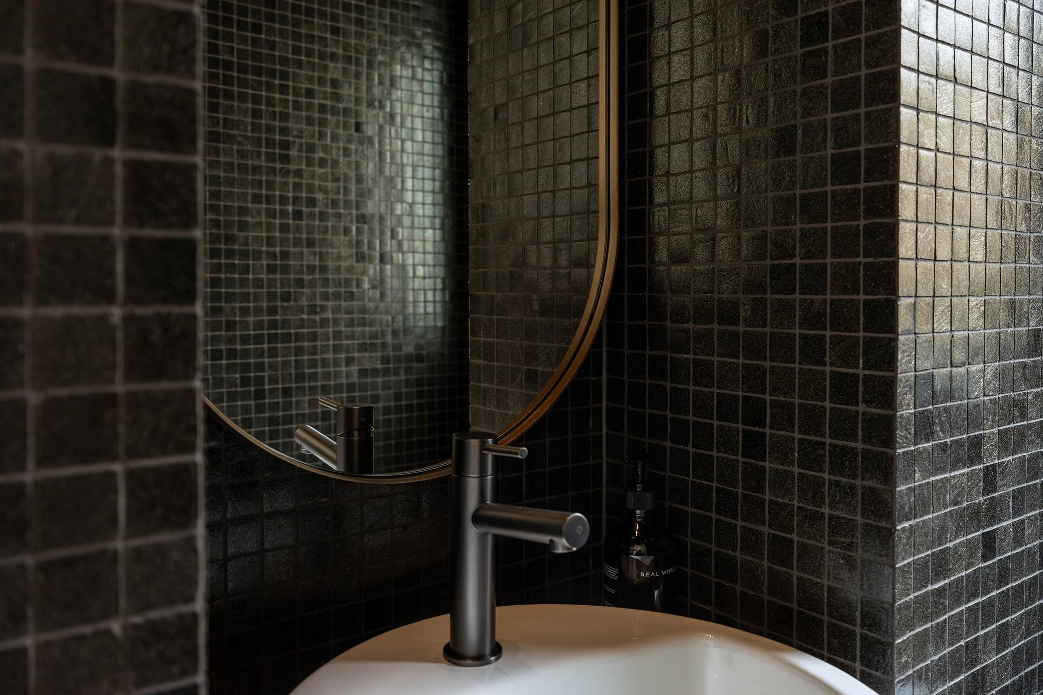 Modern residential interior design featuring powder room tiled in dark mosaic tiles