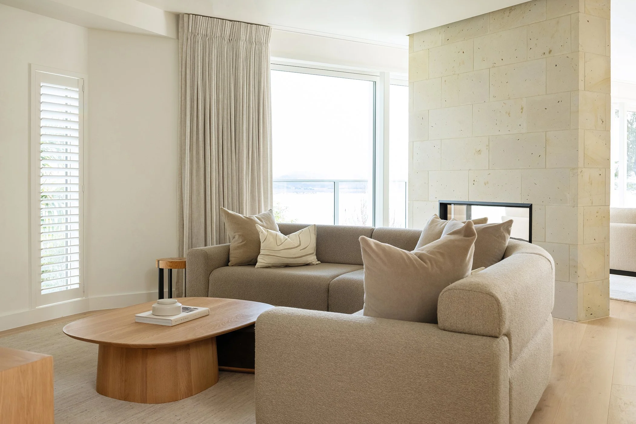 Modern residential interior design featuring a living room in neutral colour palette and stone fireplace