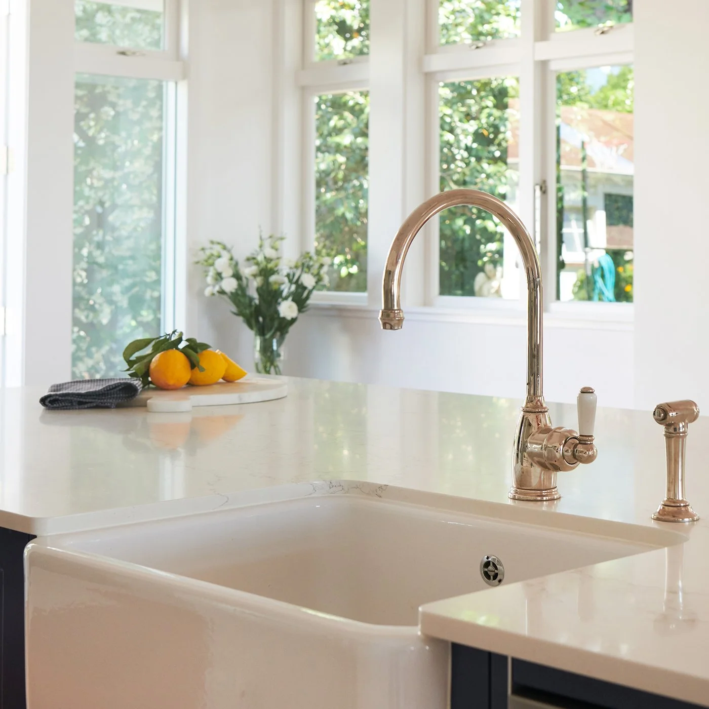 Modern residential interior design featuring a kitchen island with butlers sink and traditional gooseneck tap