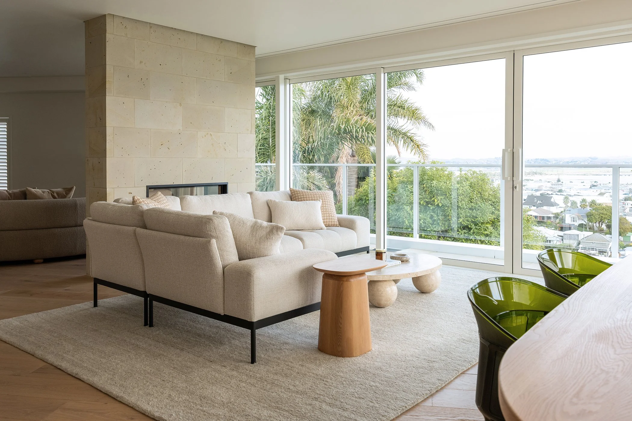 Modern residential interior design featuring a stone fireplace, corner modular sofa and Napier hilltop view