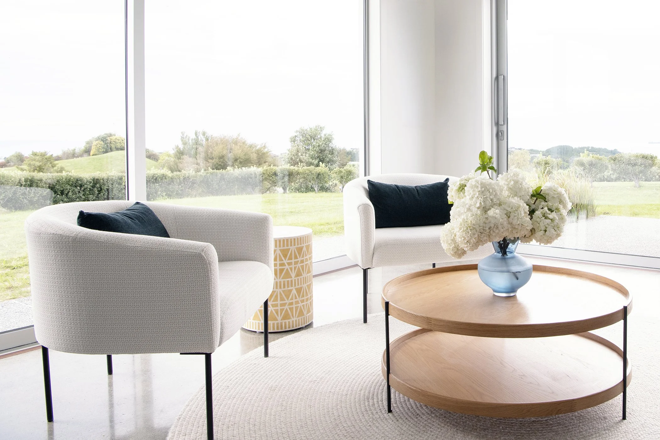 Modern residential interior design featuring a sunroom furnished with two curved armchairs and a round coffee table