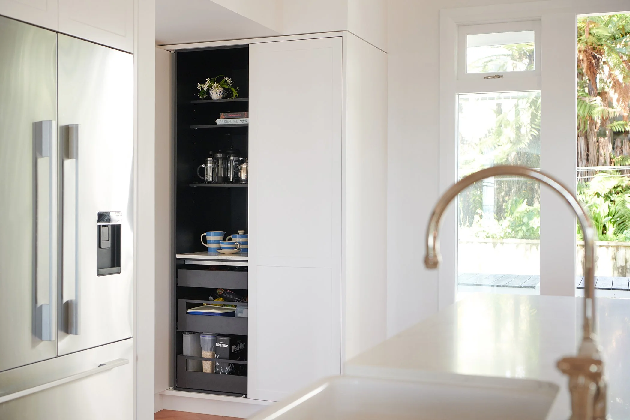 Modern residential interior design featuring kitchen with open day pantry with pocket doors