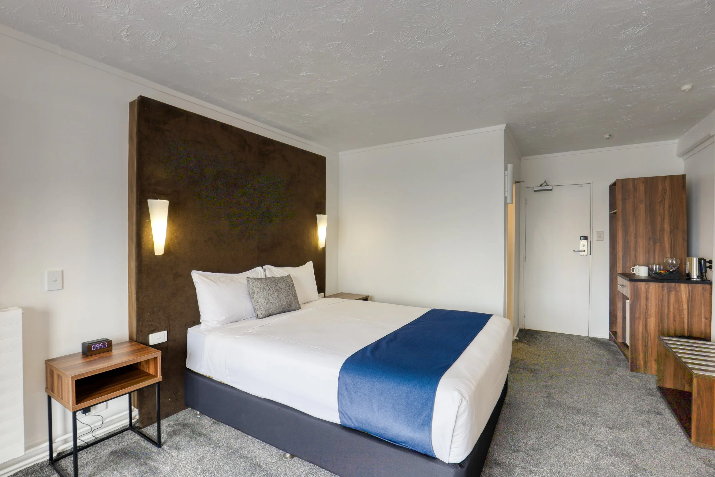 Queen bed and kitchenette area in a guest room at Park Central Rotorua.