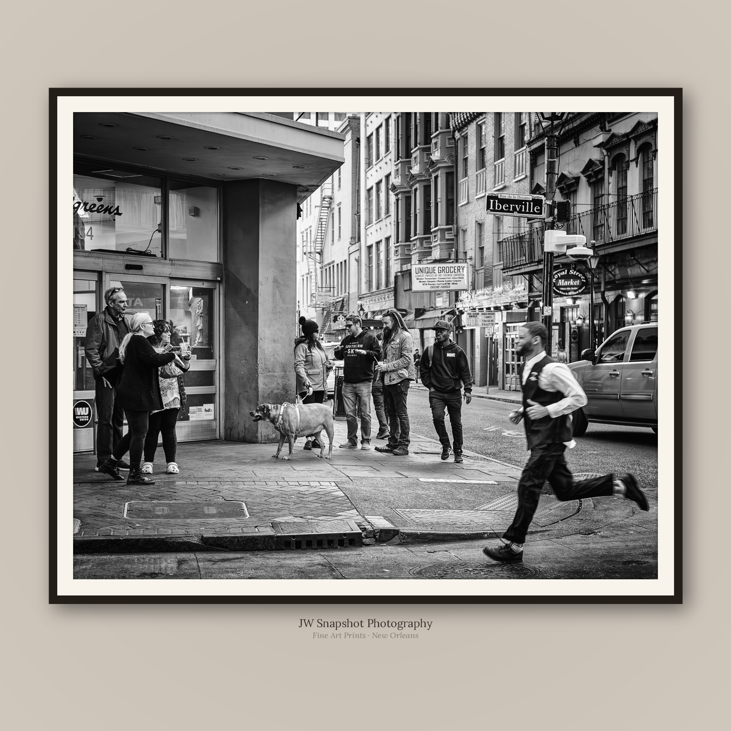 Black and white street scene in New Orleans, featuring people waiting outside a store, a dog on the sidewalk, and buildings with fire escapes and street signs that say 'Rue de la Douane' and 'Iberville'.