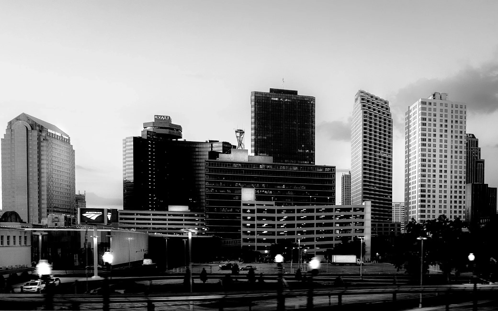 The downtown New Orleans skyline rising above an elevated road and a line of streetlights.