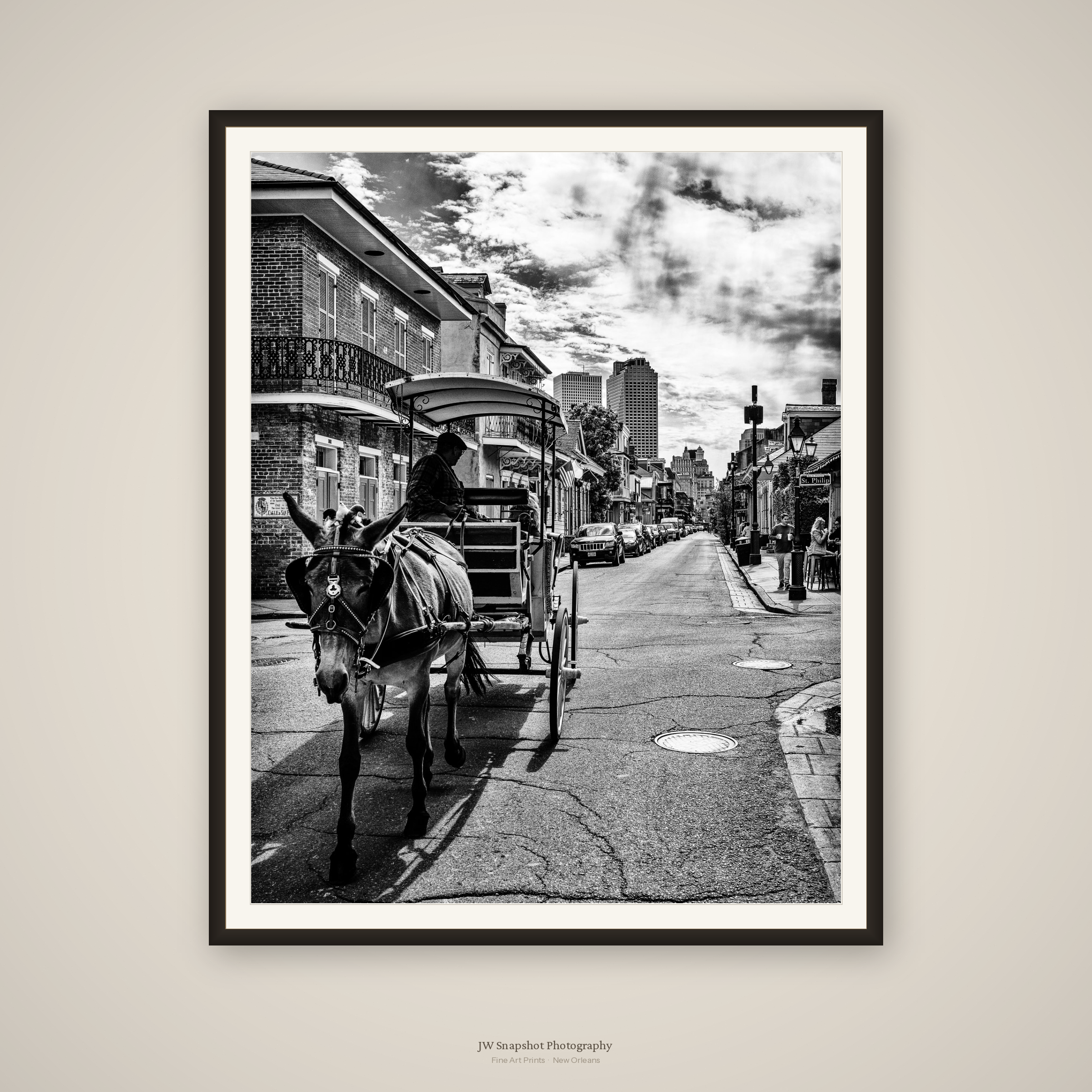Black and white photograph of a city street scene with a horse-drawn carriage, buildings, and pedestrians, under a cloudy sky.