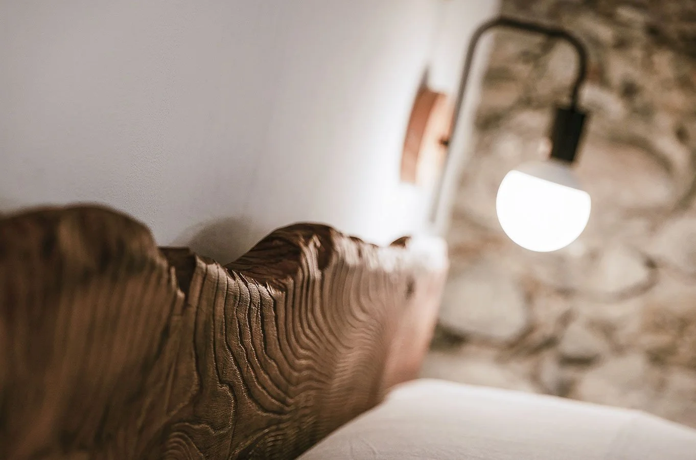 Handcrafted wooden bed and historic stone details at Palazzo Giani, blending timeless craftsmanship with contemporary comfort.