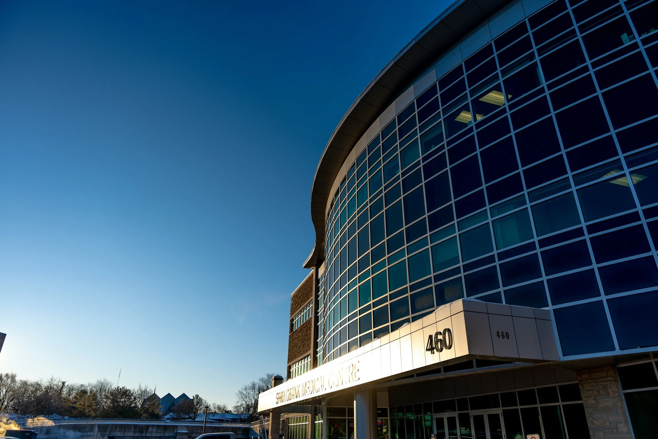 Modern building with curved glass facade at 460, sunny day with clear blue sky.