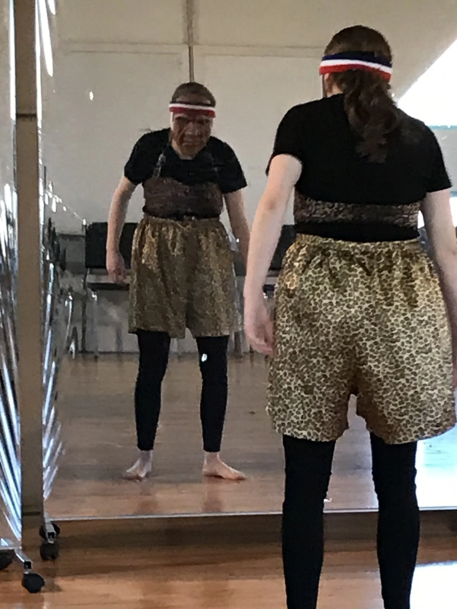 Woman wearing a mask in front of a mirror performs Alexander Technique.