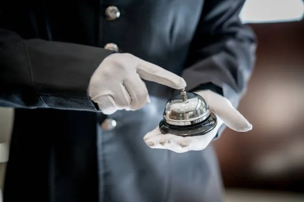 Person wearing white gloves holding a service bell in a professional setting.