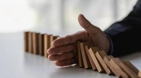 Hand toppling wooden dominoes on a table.
