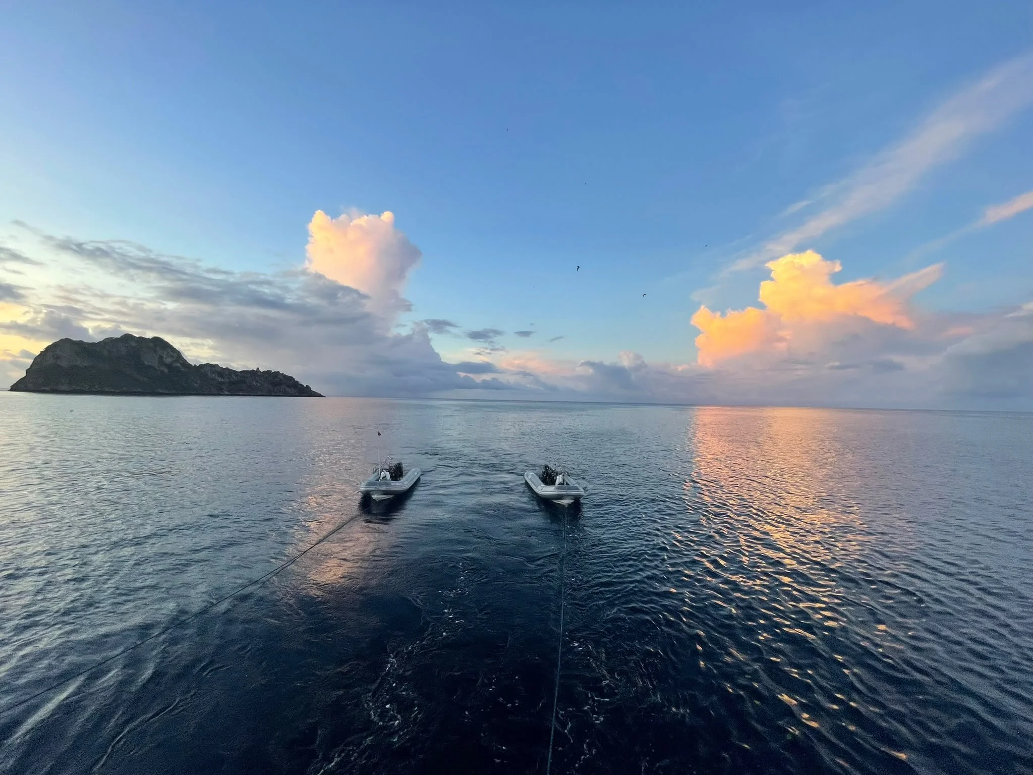 Two small boats on calm water beneath evening clouds off Cocos Island