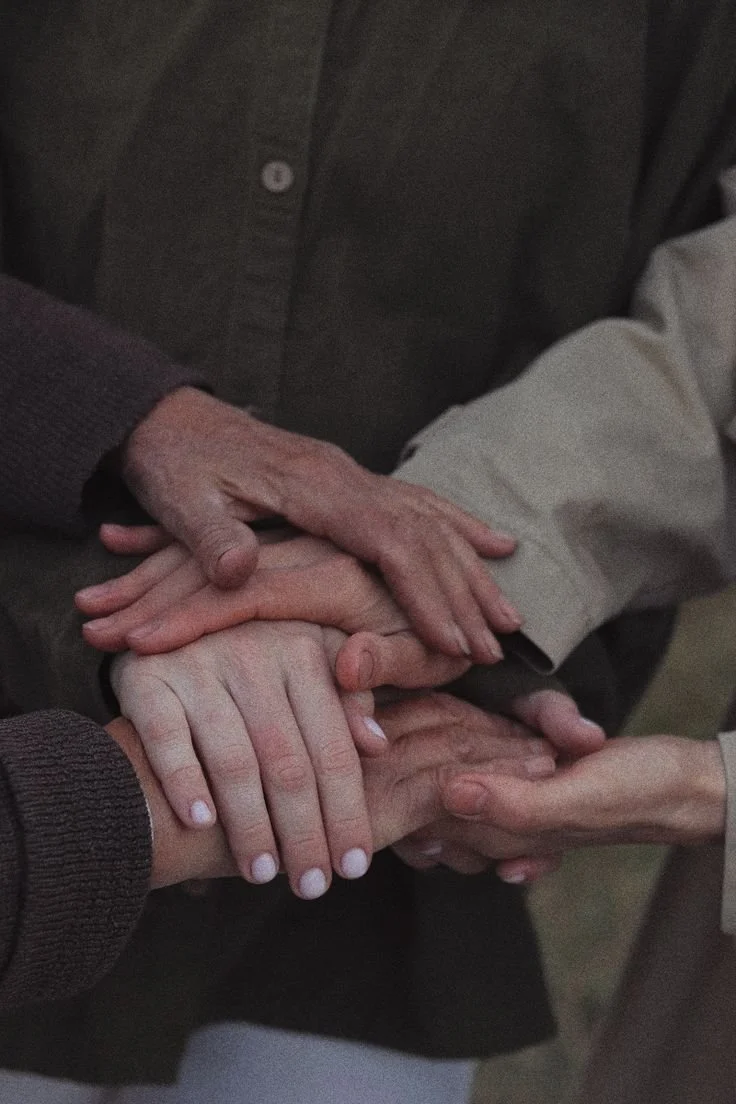 Multiple hands stacked together, symbolising unity or support.
