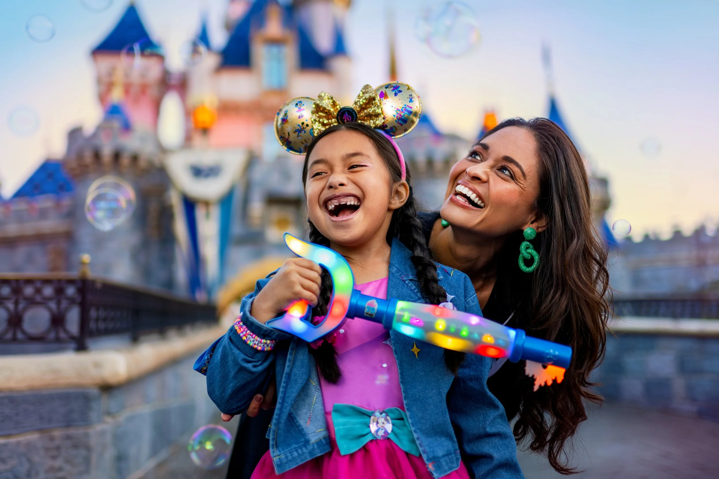 Disneyland 70th Anniversary celebration with mother and child holding interactive Key to Disneyland in front of Sleeping Beauty Castle