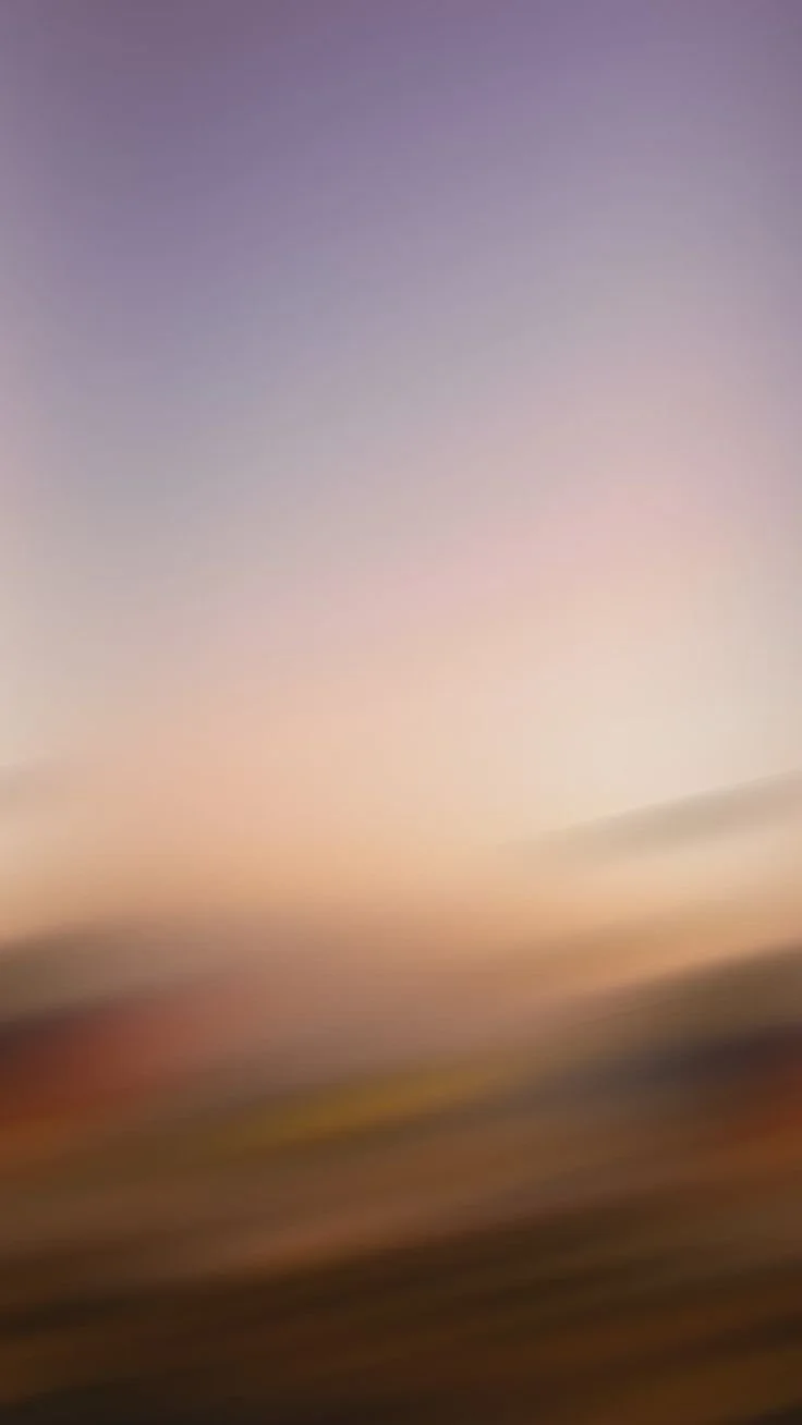 Blurred image of a colorful sky at sunset or sunrise with shades of purple, pink, and orange.