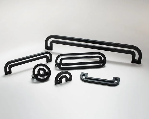 Various black metal hooks and holders on a white surface.