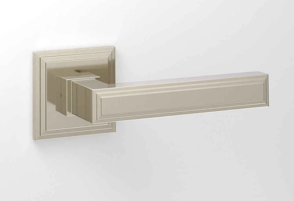 A beige door handle on a white door with a square backplate and a modern, rectangular lever design.