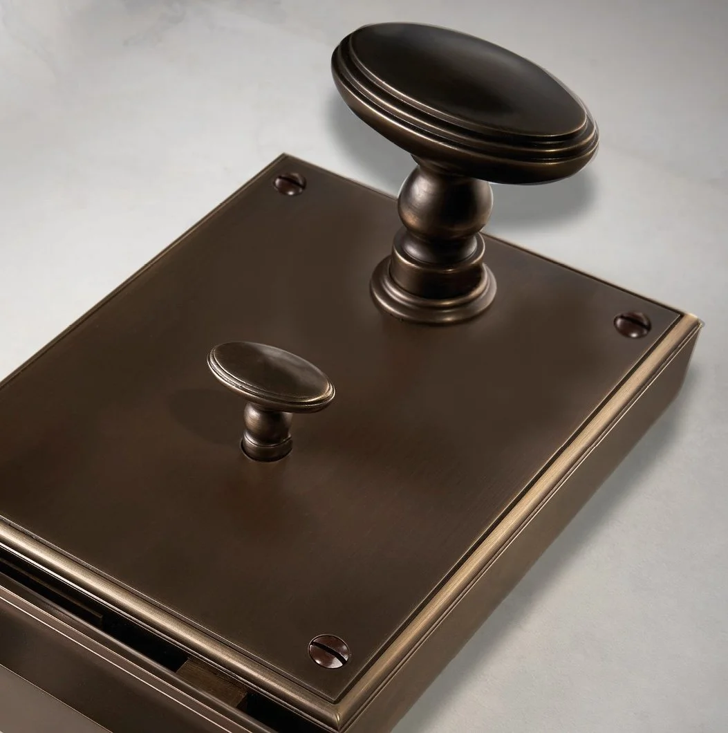 A vintage-style dark bronze or brass wall switch with two toggle switches placed on a rectangular backplate.