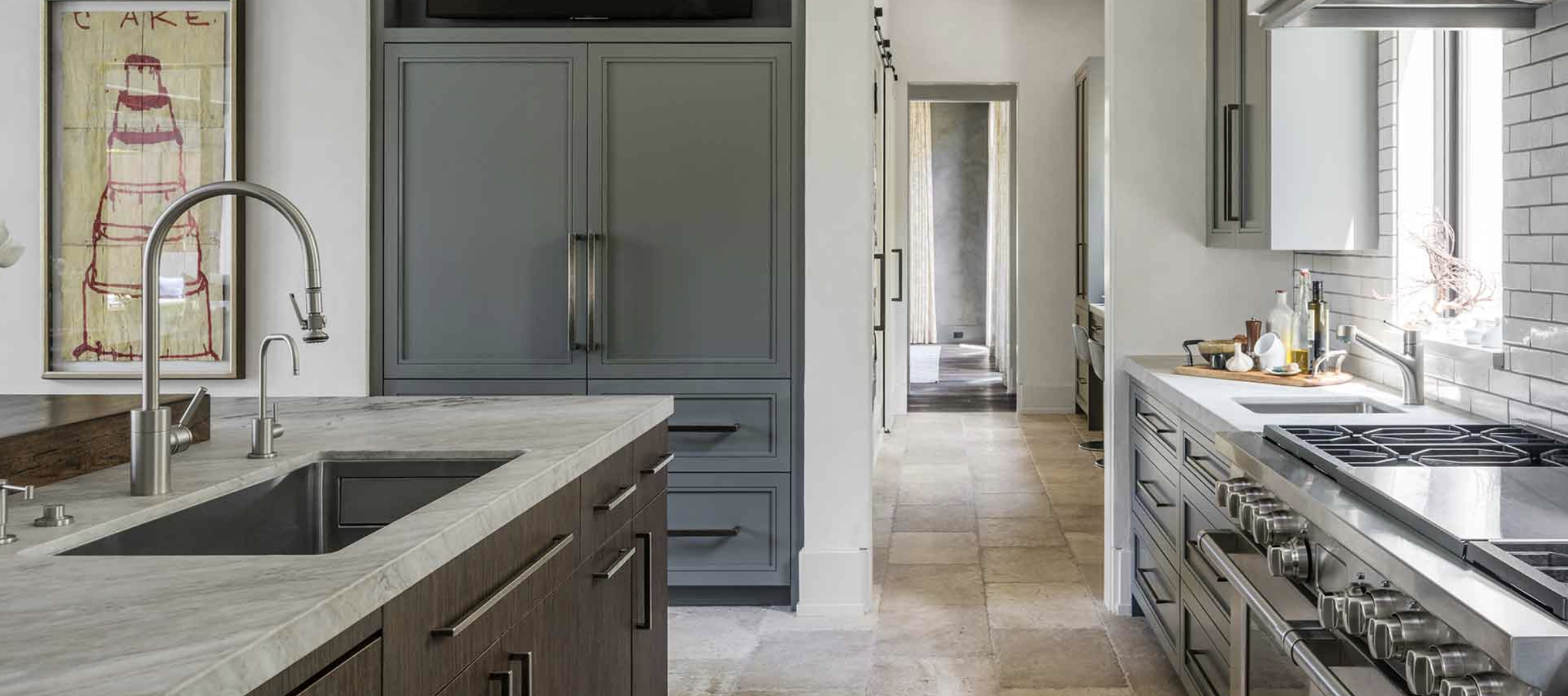 Modern kitchen with gray cabinetry, a marble countertop, and a stainless steel stove, with a window and decorative items on the counter.