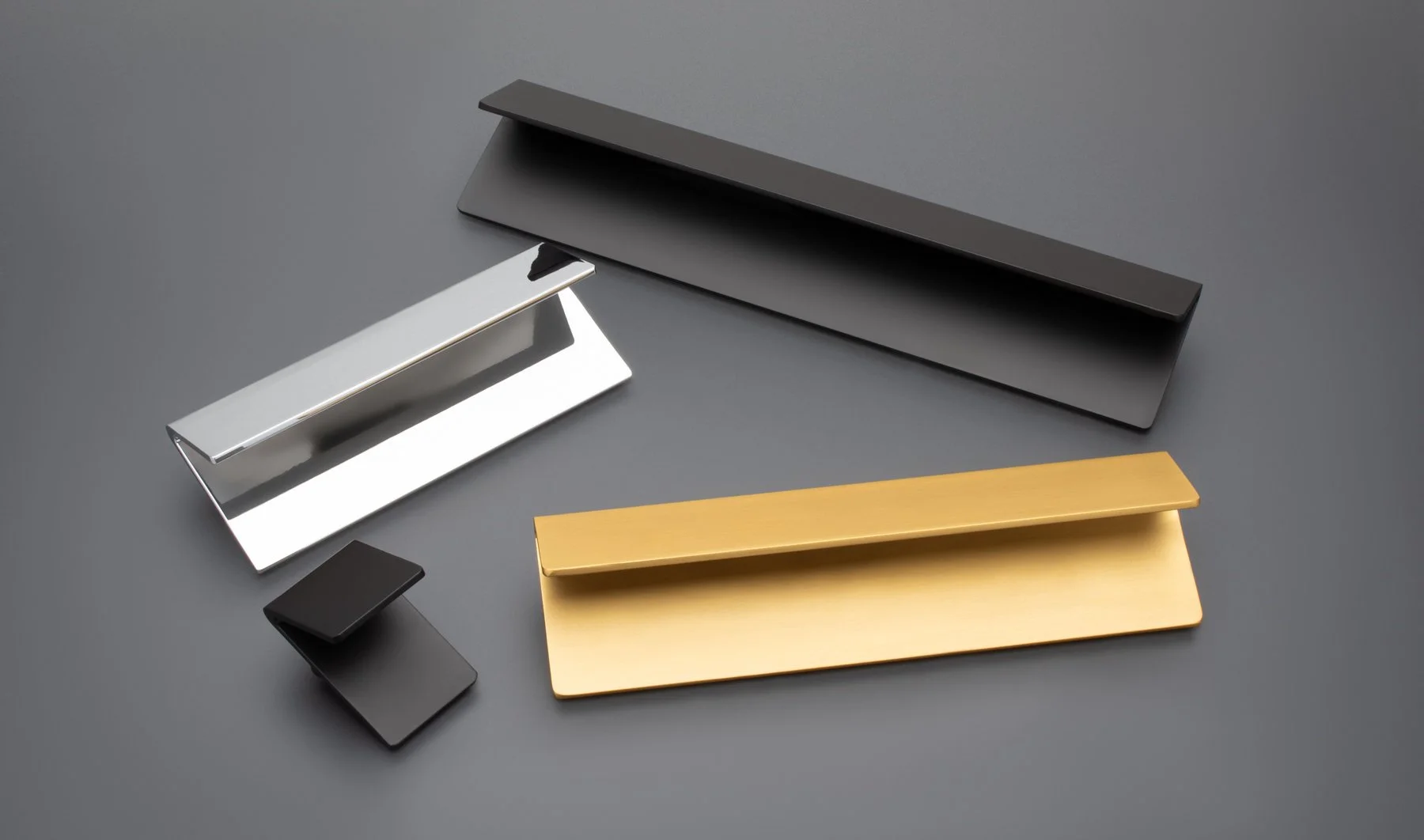 Various sleek, modern business card holders and paper clip in metallic, black, gold, and dark gray colors on a dark gray surface.