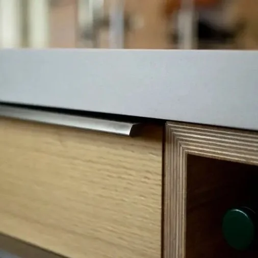 Close-up of a wooden drawer with a silver handle and a white countertop on top.