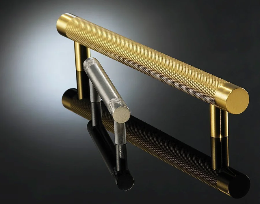Close-up of a gold and silver textured metal door handles on a reflective black surface.