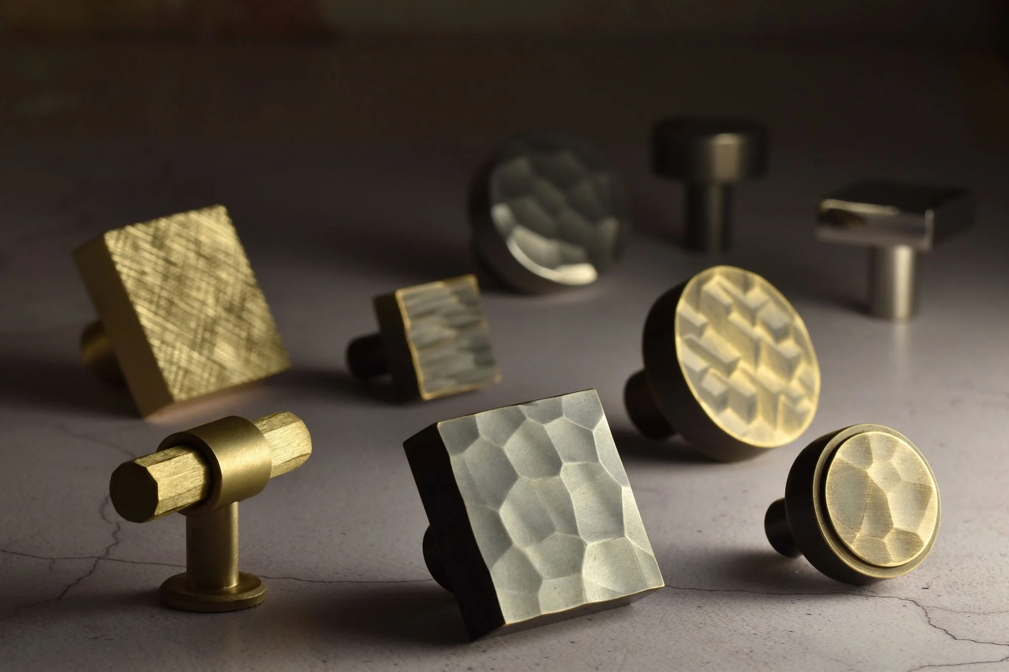 Assorted metallic decorative objects with various textured patterns and shapes, displayed on a neutral surface.