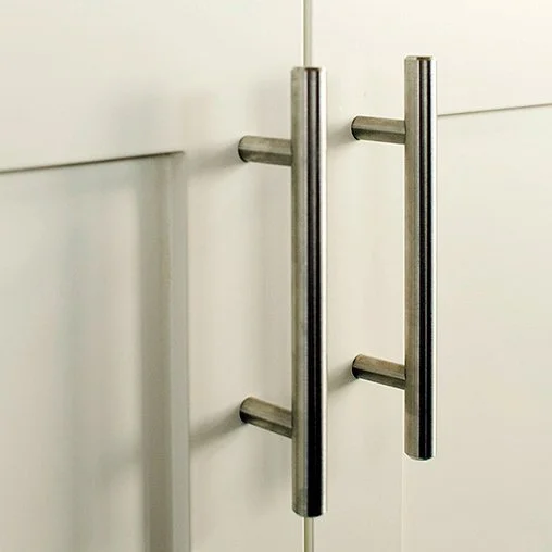 Close-up of modern kitchen cabinet handles on white cabinets.