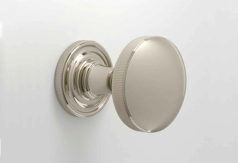 A silver door knob on a white door.
