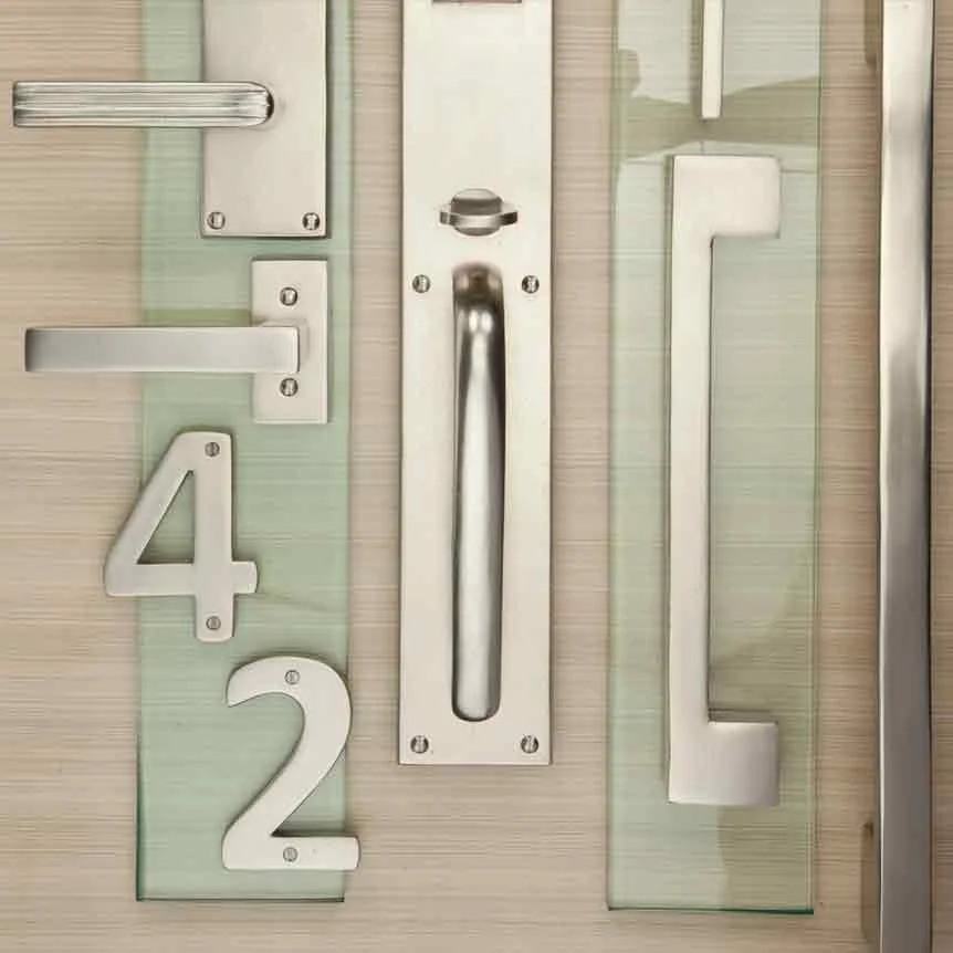 Various door hardware components including handles, locks, and plates arranged on a wooden surface.