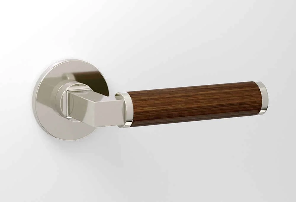 Door handle with a wooden grip and metallic base mounted on a white door.