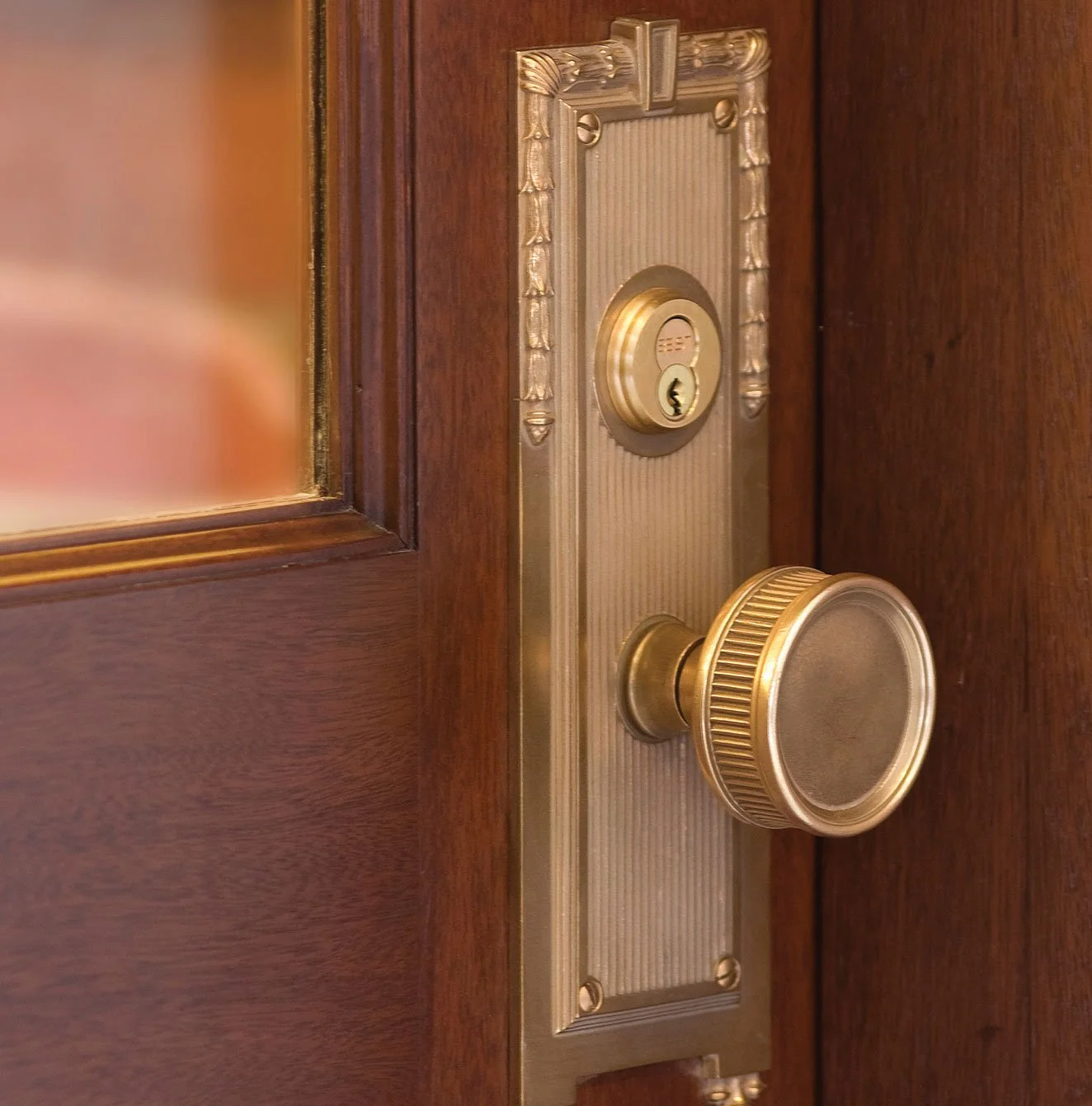 Close-up of a vintage door lock with a brass knob and keyhole on a wooden door.