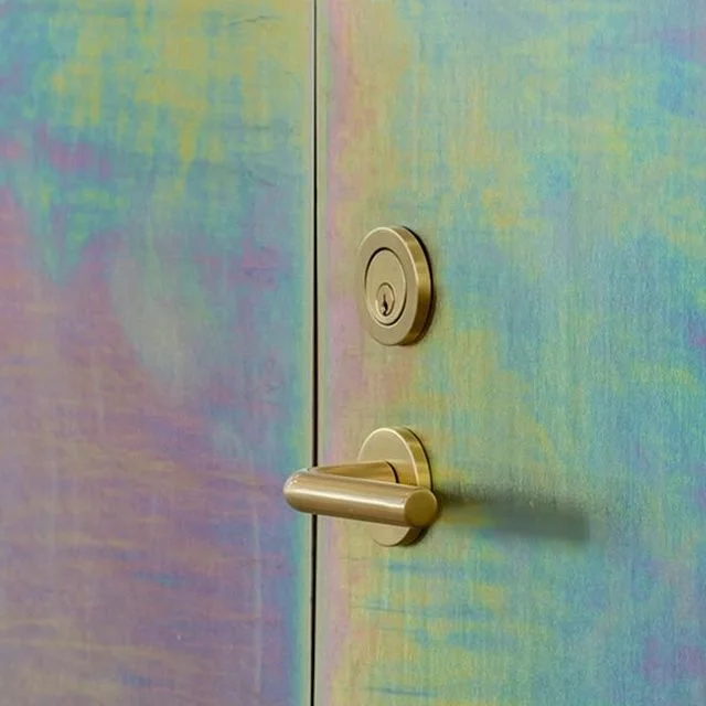 Close-up of an iridescent door with a round lock and a horizontal door handle.