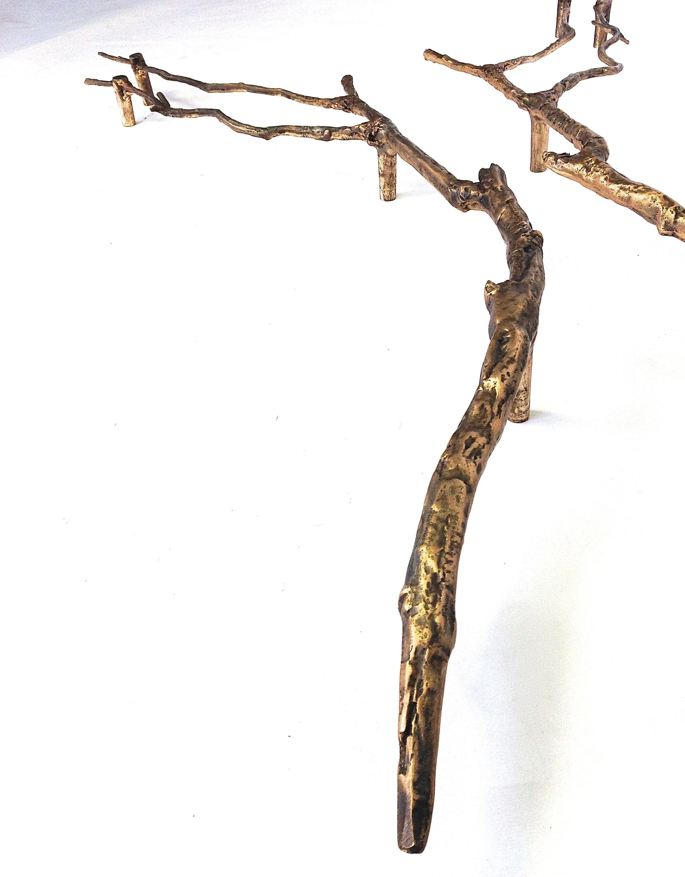 A rusty, twisted metal sculpture resembling a tree branch on a white background.