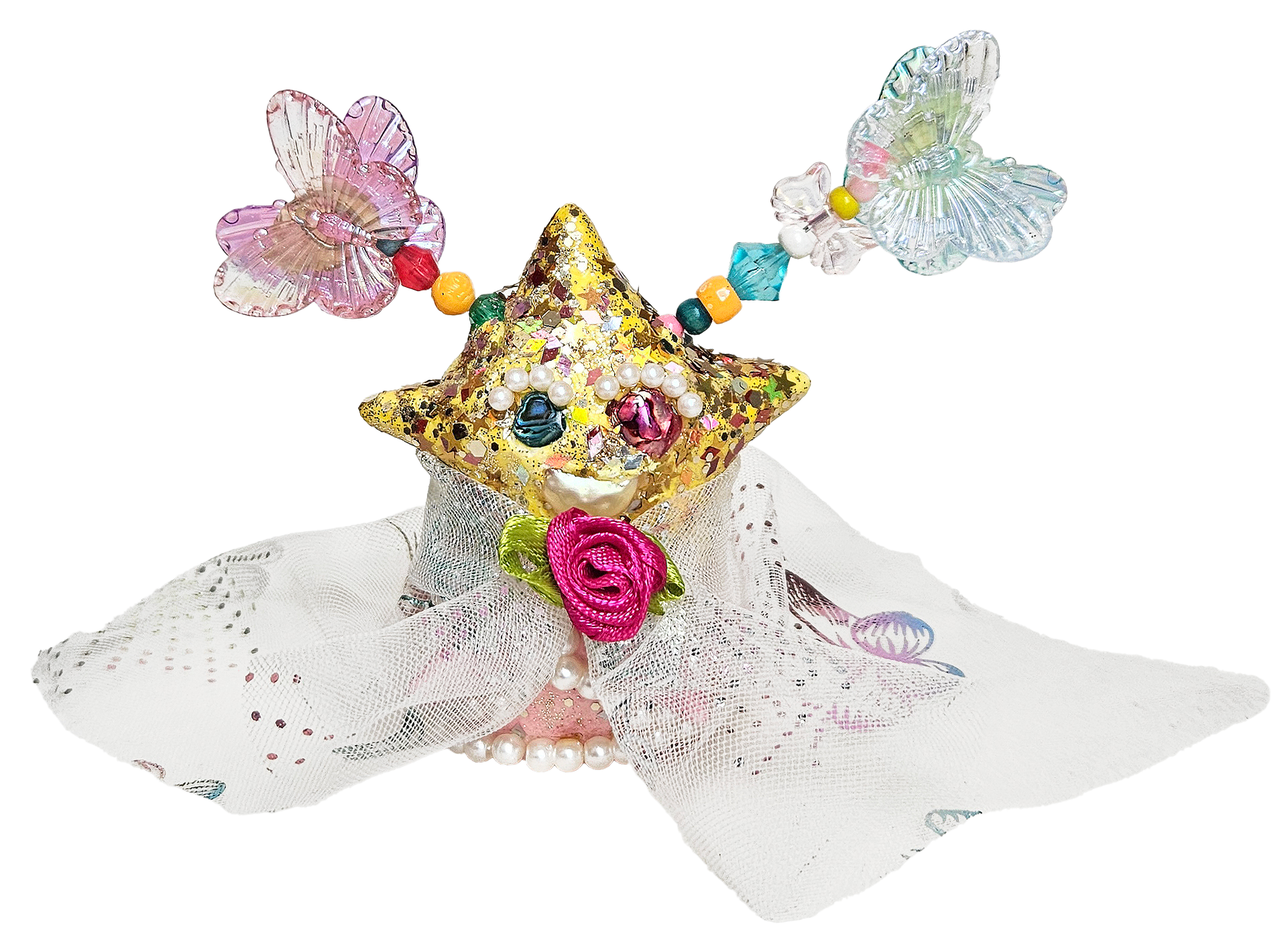 Decorative arrangement featuring two iridescent butterfly ornaments, a gold glittery star-shaped object, colorful beads, faux pearls, pink ribbon roses, and lace fabric, all set against a black background.