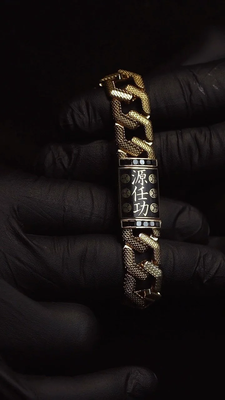 A gold-colored chain bracelet with a rectangular black plaque featuring Chinese characters.