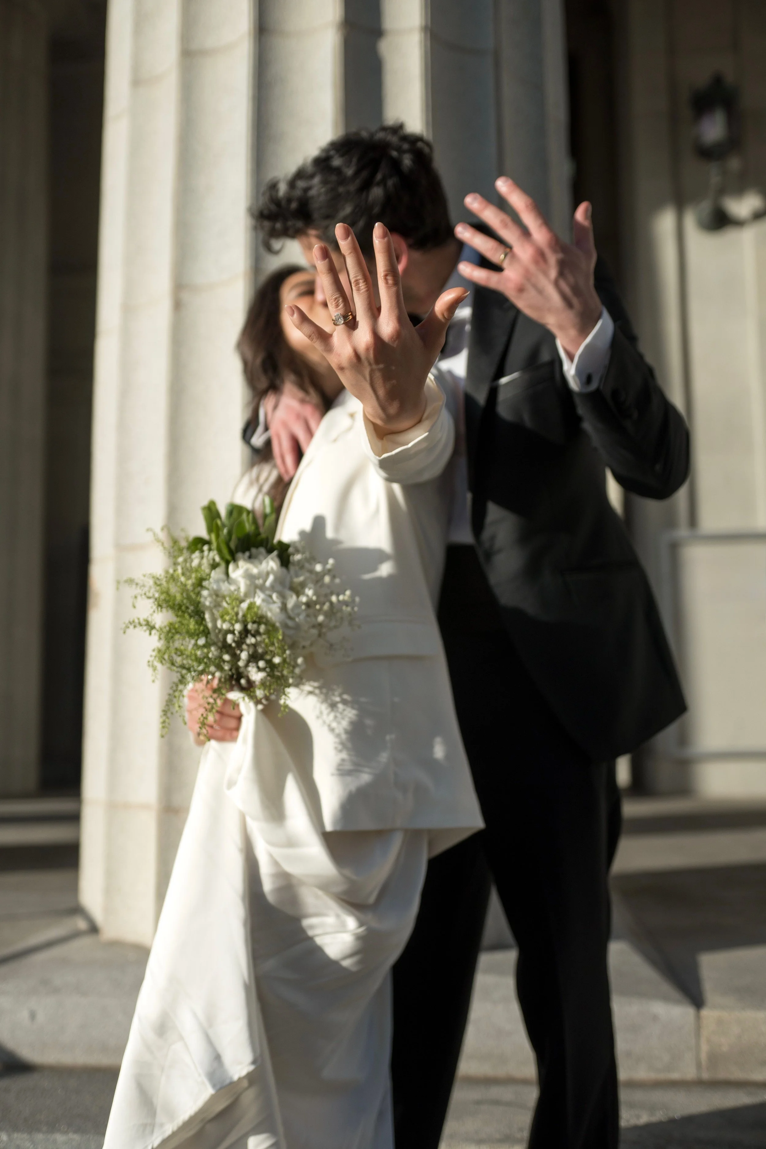 an Asian straight couple kissing and showing off rings on wedding day