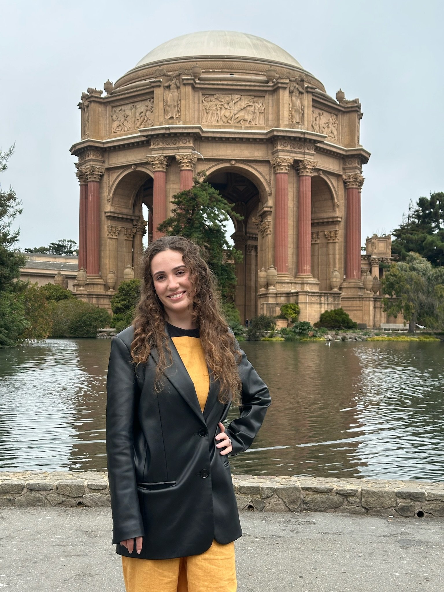 A long haired brunette woman standing in front of the Palace of Fine Arts in San Francisco