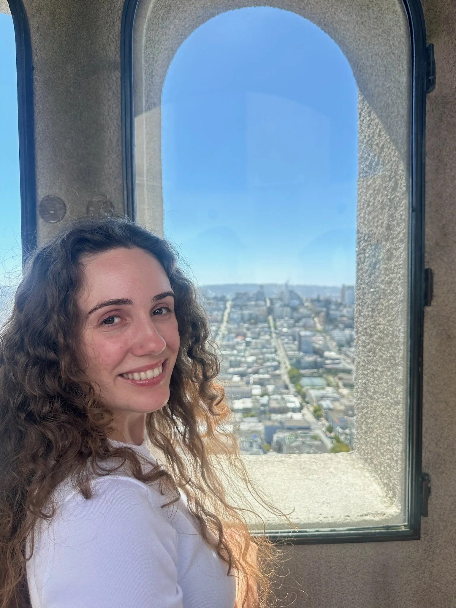 woman in Coit Tower looking at San Francisco skyline