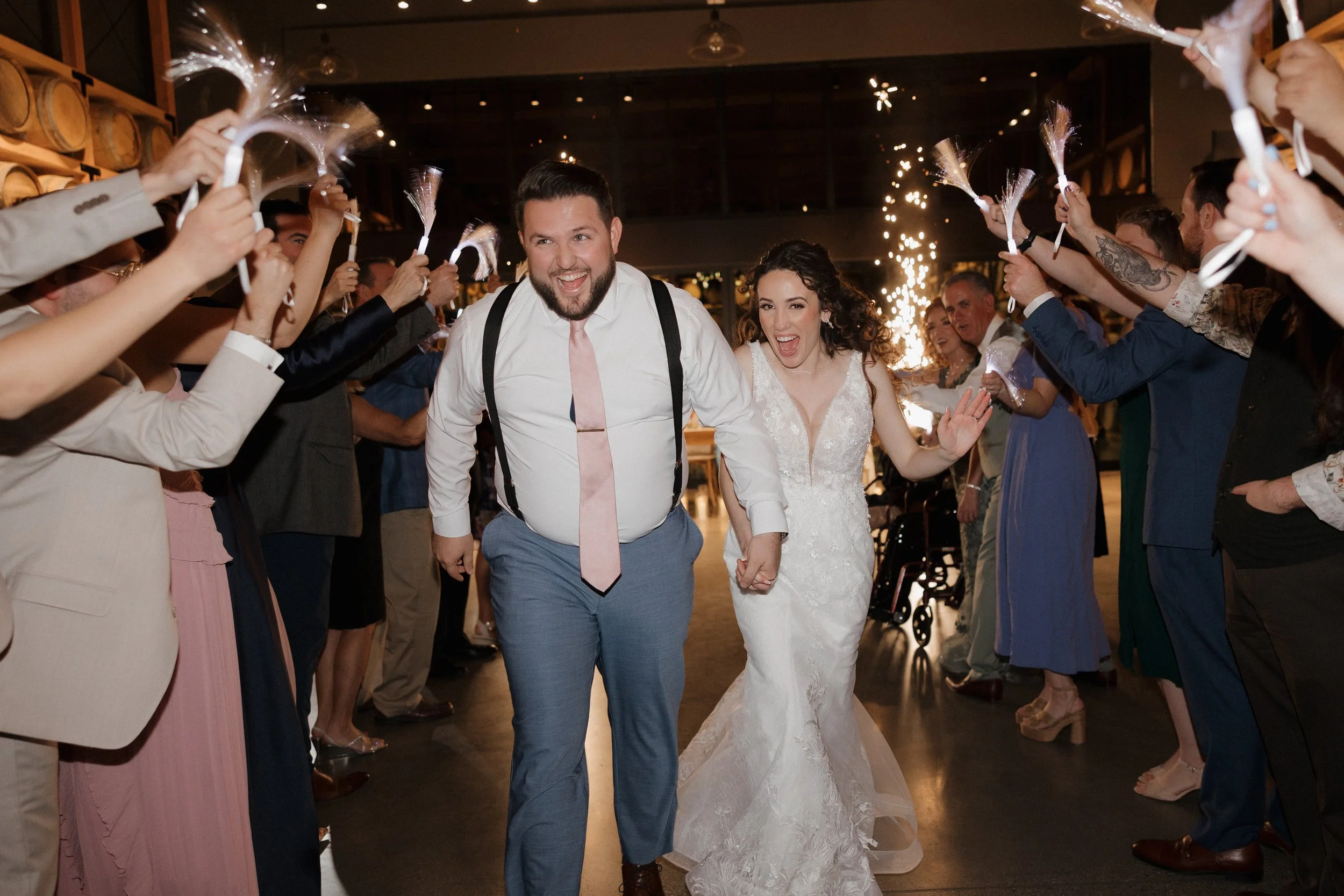 couple doing grand exit with families holding sparklers on wedding day