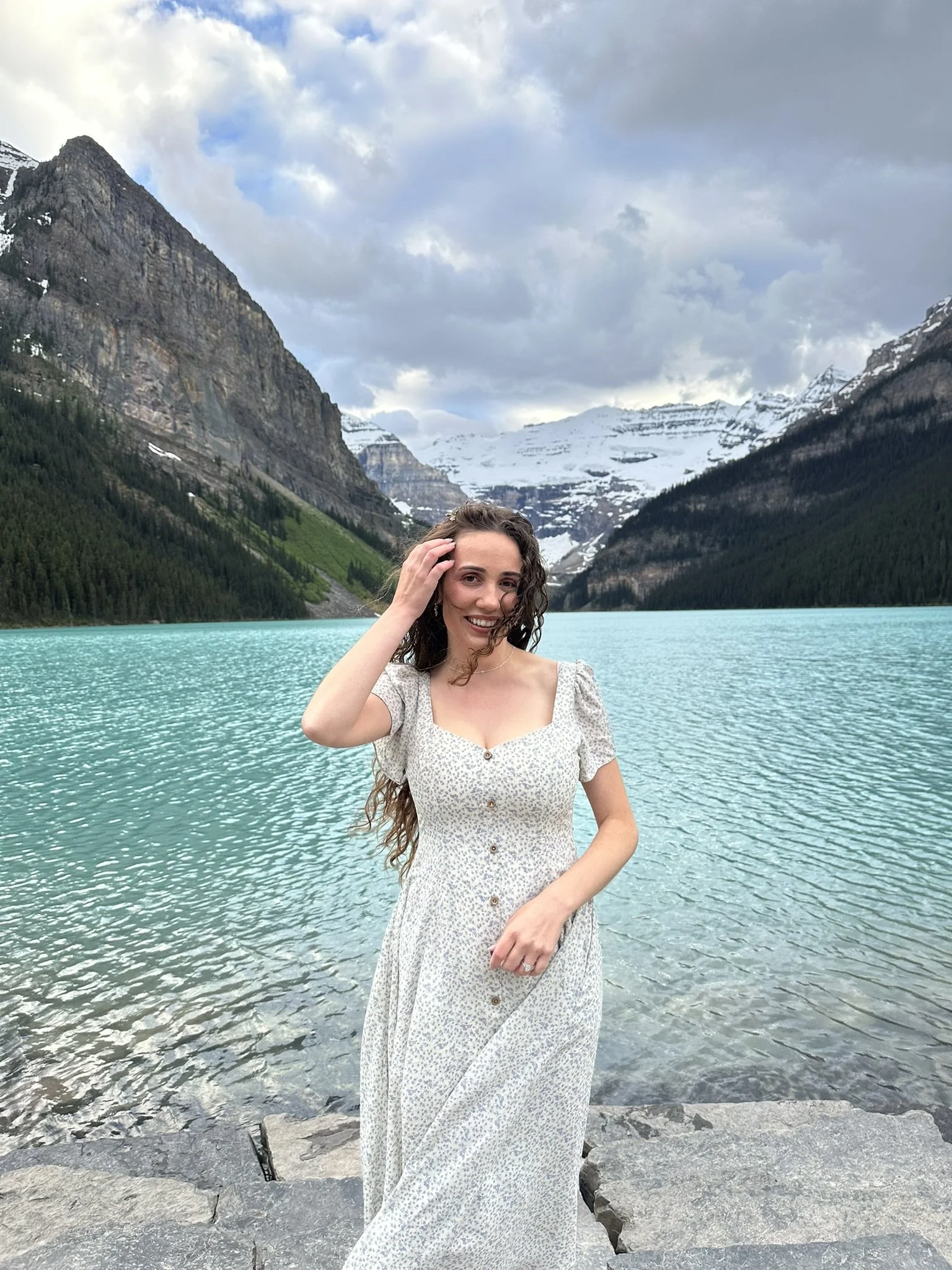 woman in white dress standing in front of Lake Louise
