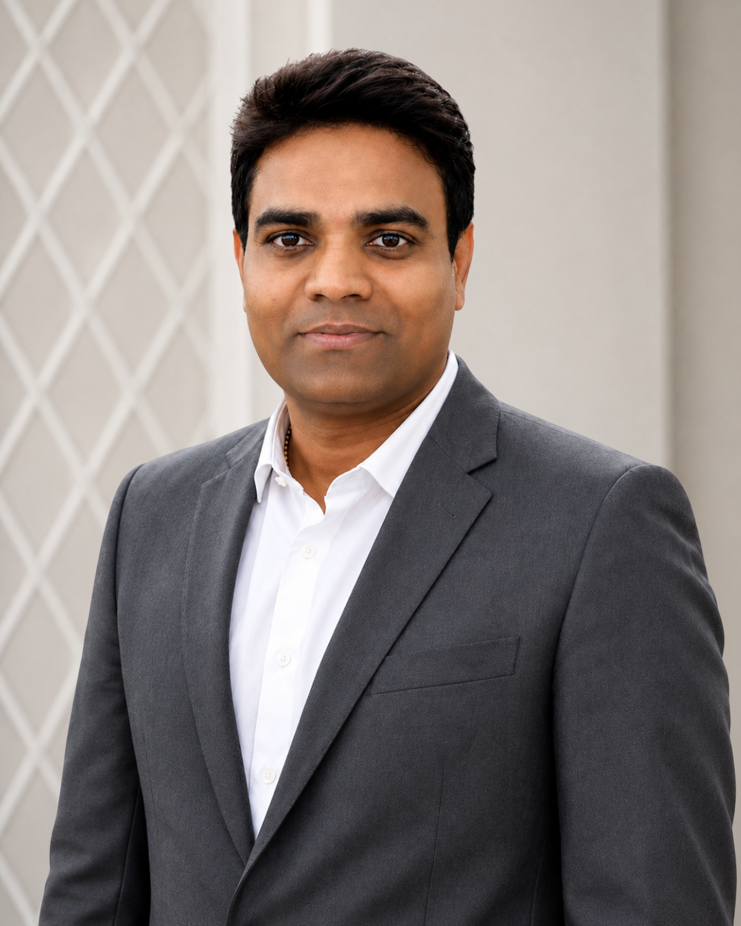 A man in a gray suit and white shirt standing outdoors with a neutral expression