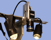 A zoom or microscope setup with cameras and lights against a blue background.