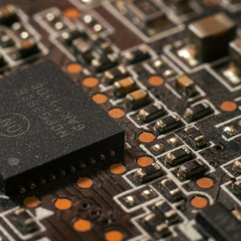 Close-up of a computer circuit board with a black integrated circuit chip and various electronic components and connections.