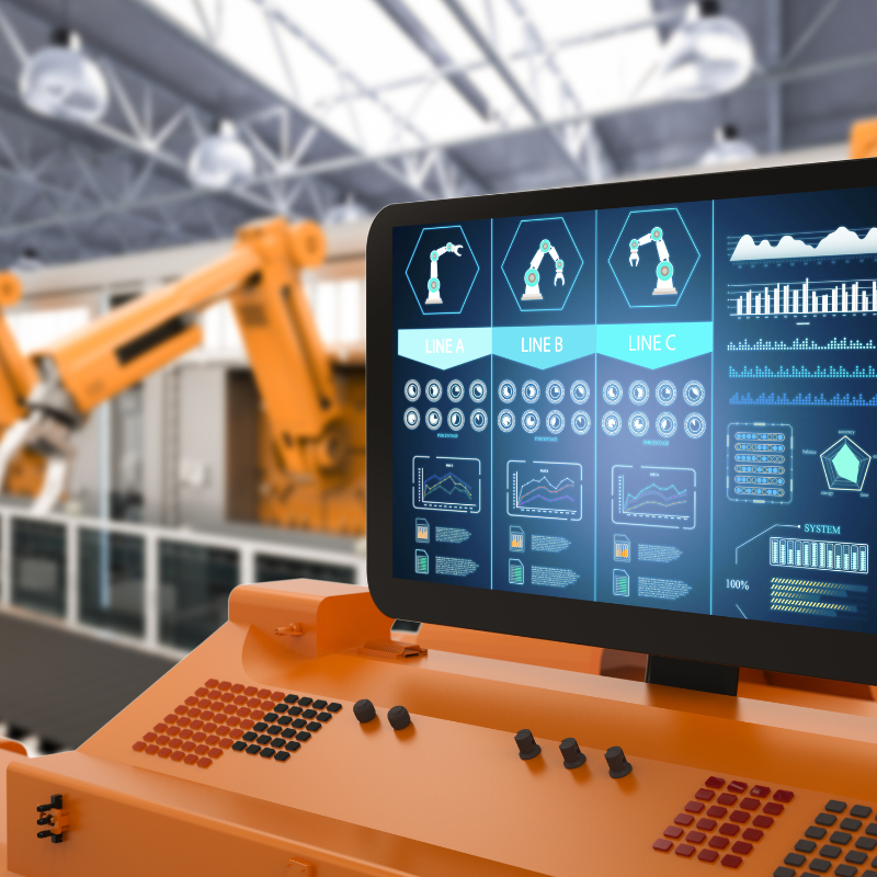 Control panel with a computer monitor displaying industrial data and robotic arms in an automated factory setting.