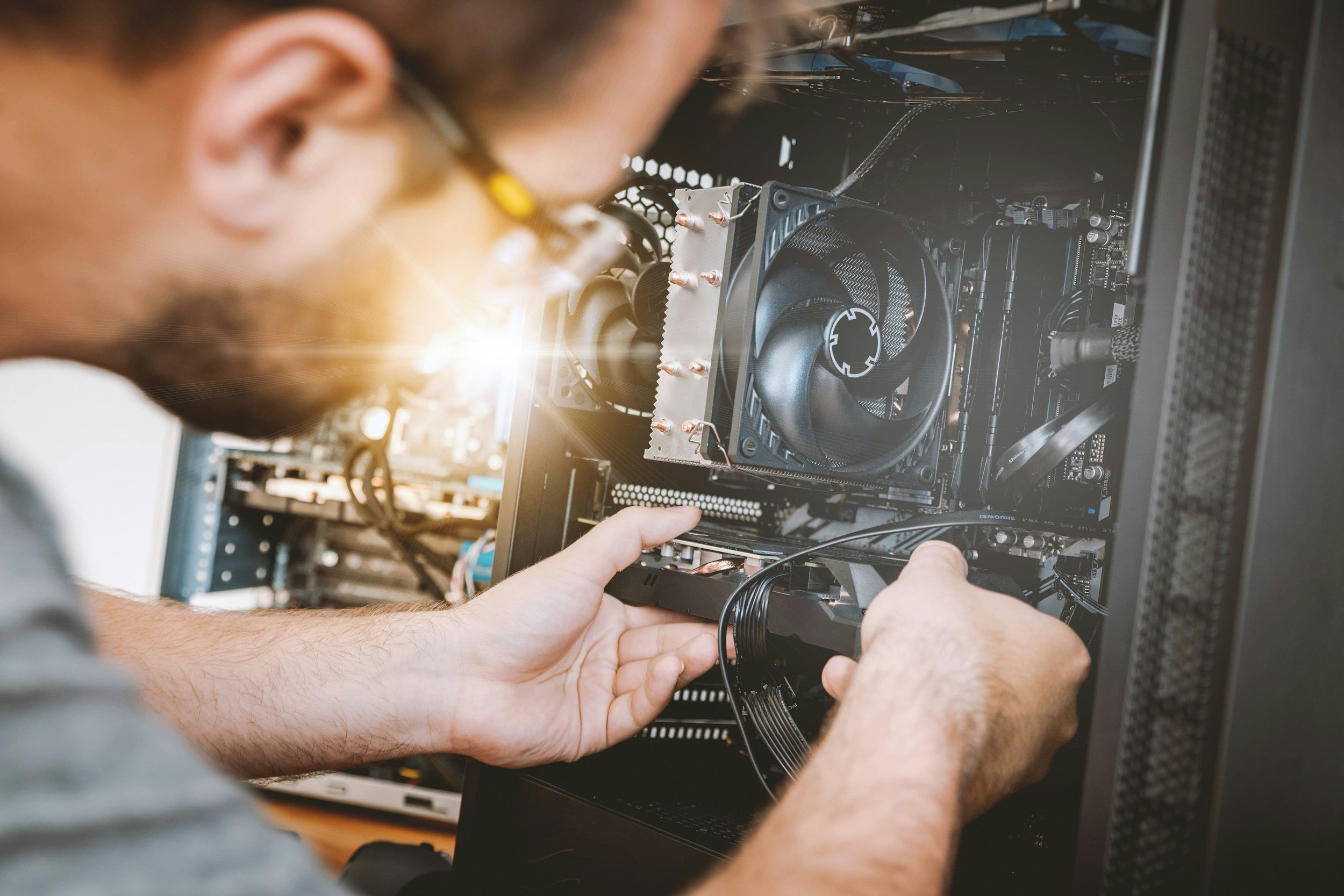 A person installing or repairing computer hardware inside a desktop computer case, focusing on the internal components.