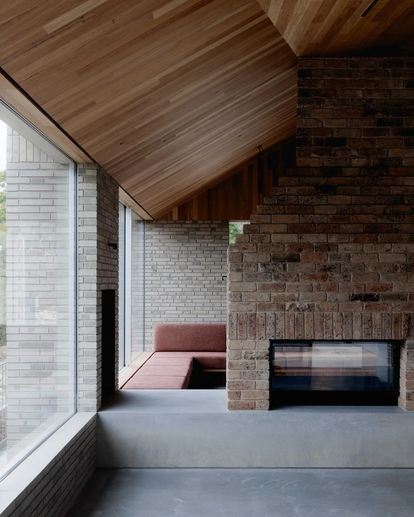 The fireplace was a key part of the design brief for our clients, serving as both a functional and symbolic element. Salvaged bricks from the original house, carefully sorted and laid by the bricklayers, reference the old hearth, reimagined in a cont