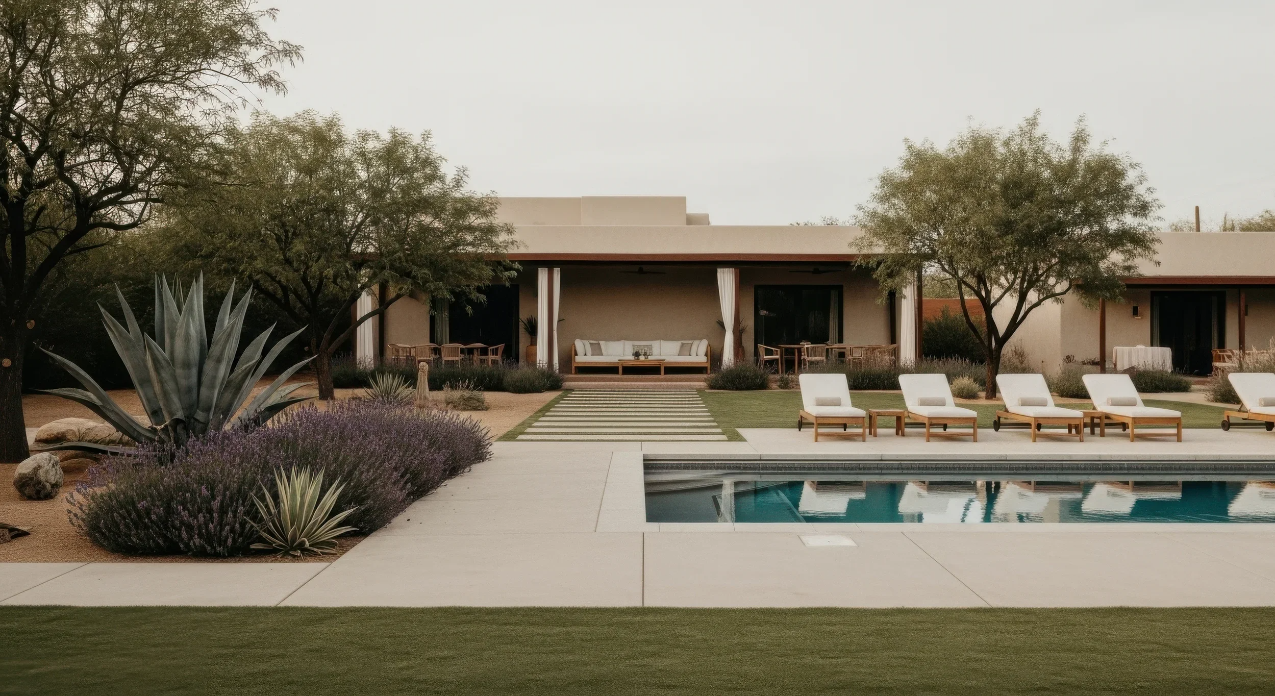Luxury spa with a swimming pool, lounge chairs, patio seating, and desert landscaping including agave and lavender plants.
