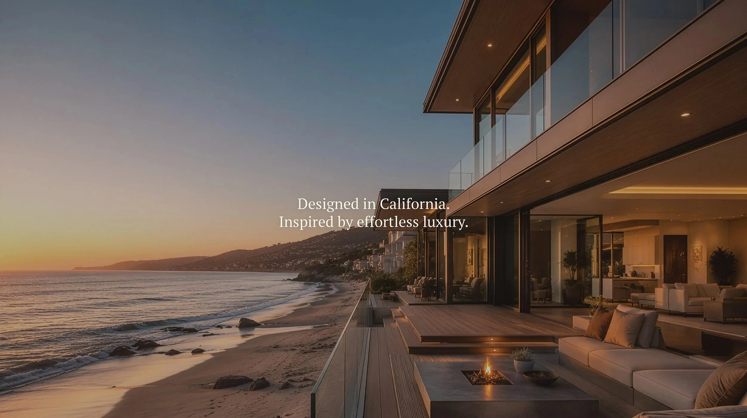 Modern house with glass exterior overlooking a beach at sunset, interior visible with couches, plants, and a fire pit. Text says 'Designed in California. Inspired by effortless luxury.'